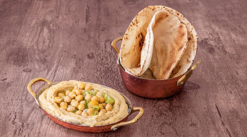Houmous libanais maison préparé avec pois chiches, tahini et huile d'olive, servi avec pain pita frais chez King Libanais Maison des Galettes à Paris 10.